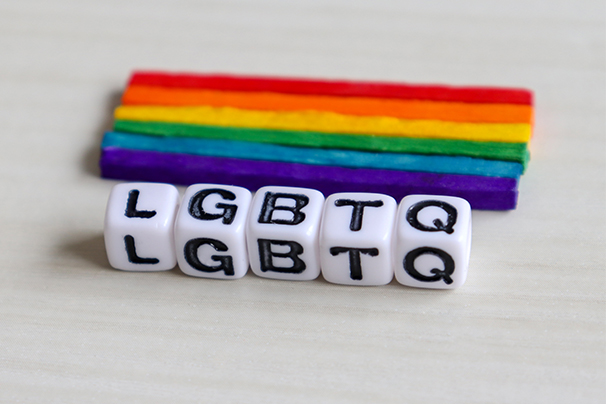 Individual letter dice arranged to spell out LGBTQ with a rainbow behind.